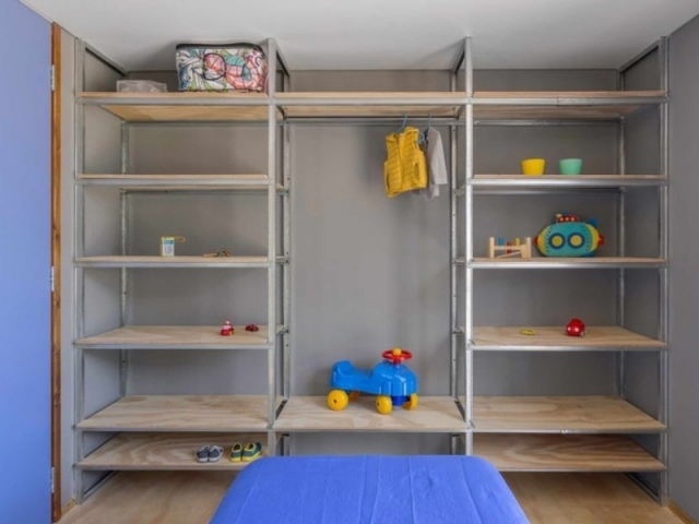 Casa Cronos - Moirë arquitectos - Dormitorio cómodo con estantería de madera y metal.
